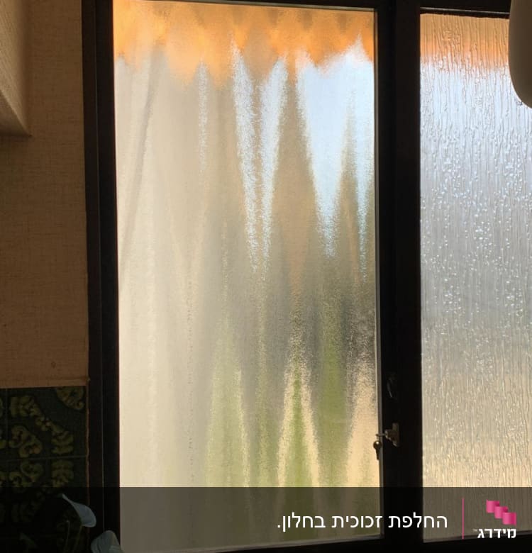 חלון זכוכית עם דוגמה מטושטשת ואור שמש